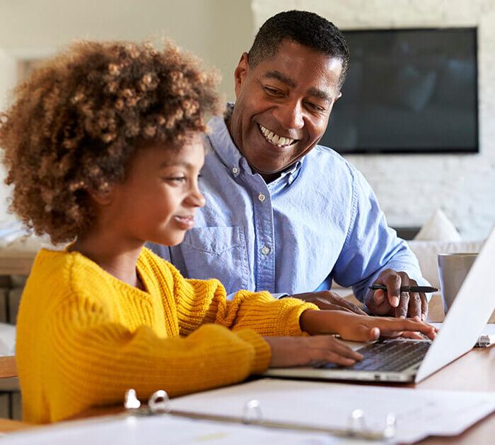 一位父亲用笔记本电脑帮助女儿做功课