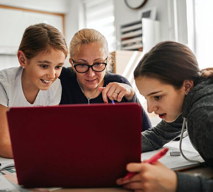一位母亲正在帮助她的两个女儿做网上作业