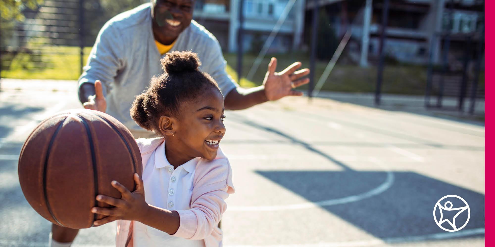 一个小女孩正在和她爸爸打篮球